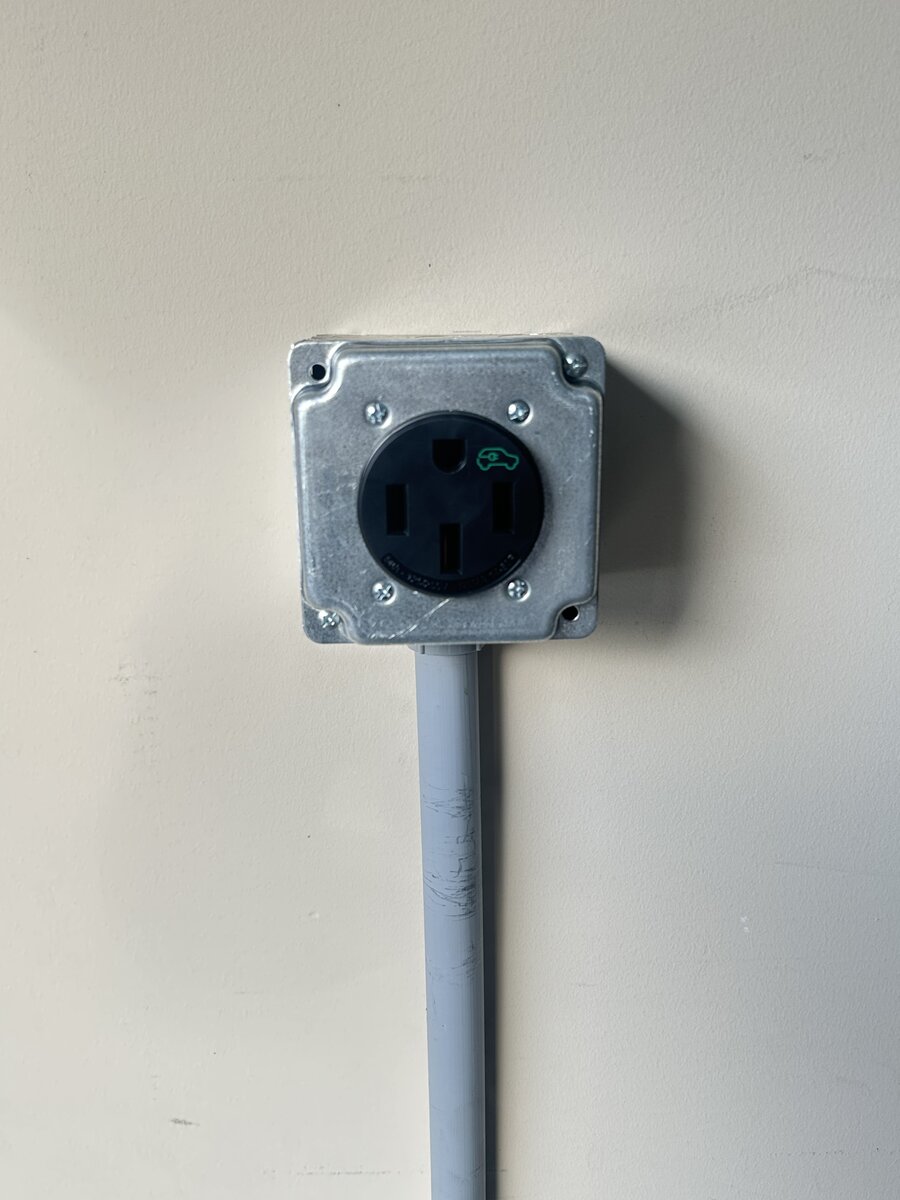 Tesla Wall Connector installed next to parked vehicle